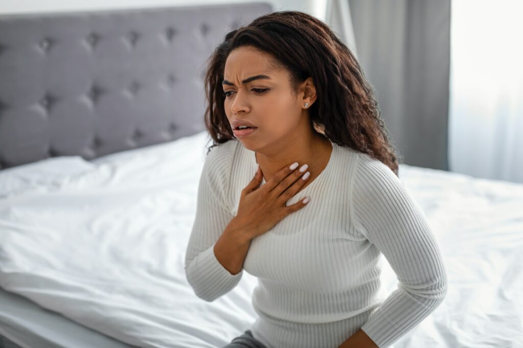 Young black woman coughing, suffering from sore throat