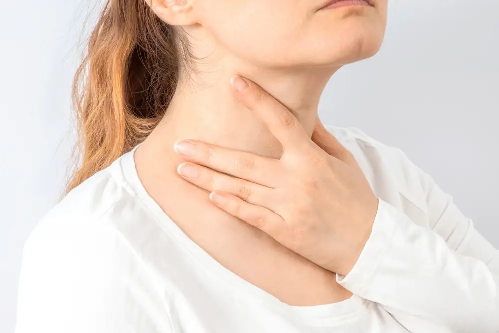 woman holding her neck, thyroid health